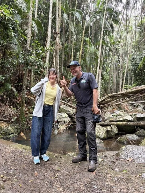 タンボリン山の熱帯雨林でガイドと写る参加者
